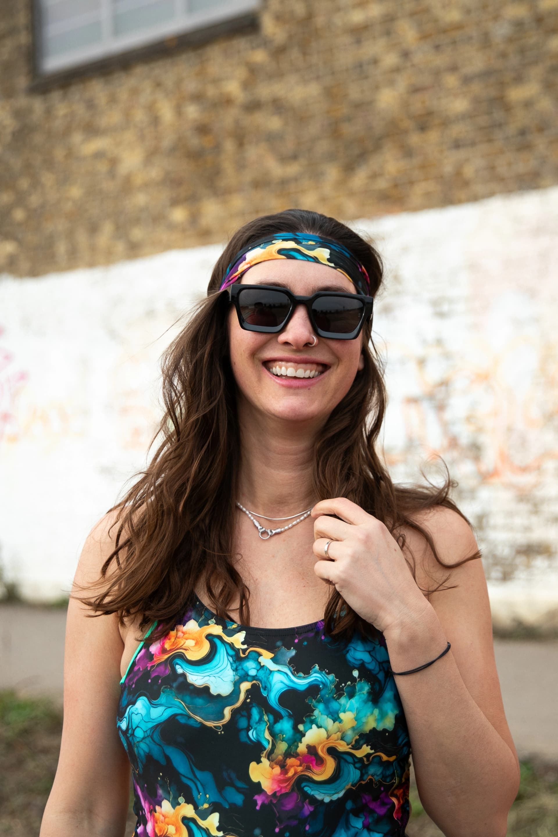 A smiling open-water swimmer in sunglasses and a colourful swimsuit